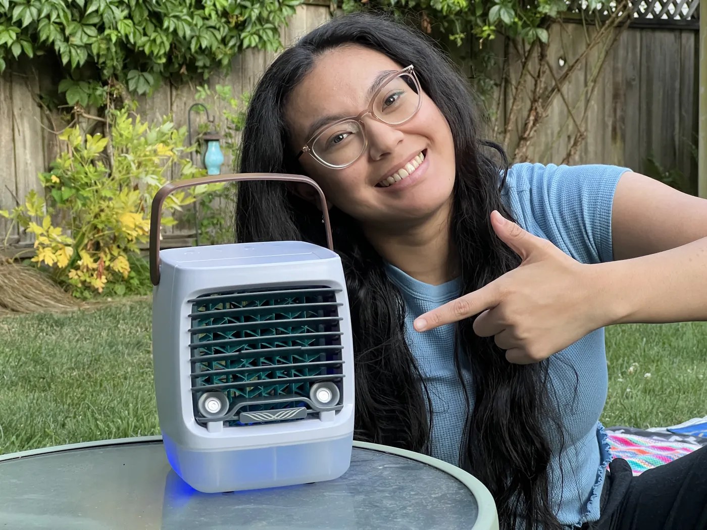 A tester pointing at the Cwell 2.0 running on a patio table